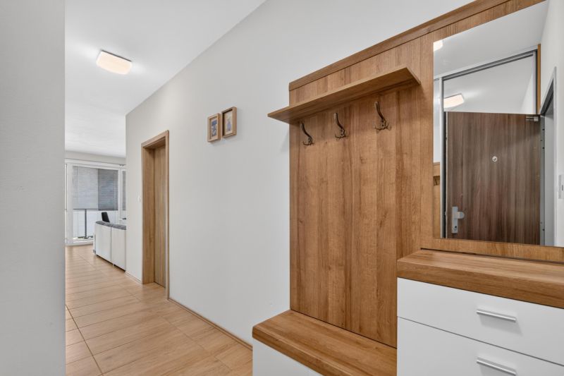 Predaj 2-izbový byt GREEN VILLAGE, loggia, parkovanie, Dunajská Lužná - Vstupná chodba v 2-izbovom byte s podlahou s dreveným dekorom a vešiakovou stenou.