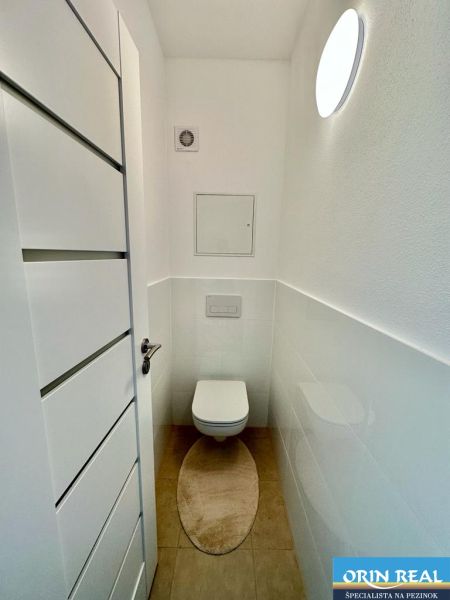 NOVÝ KRÁSNE ZARIADENÝ BYT s parkovacím miestom - Toaleta s podlahou s dreveným dekorom v 2-izbovom byte.