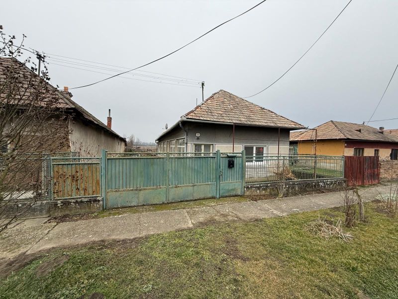 DOM NA PRENÁJOM, Obec Sikenica, okres Levice - Rodinný dom v Sikenici so starším plotom a záhradou, obklopený ďalšími domami.