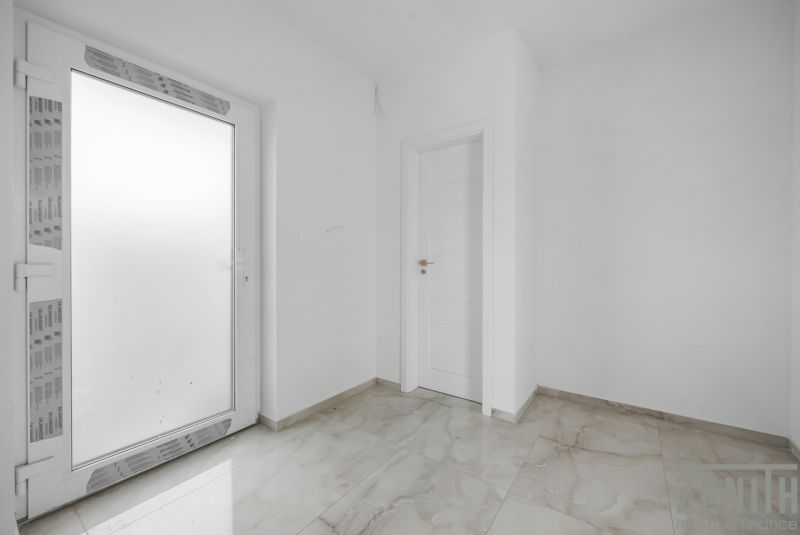 Moderný rodinný dom, ktorý vás prekvapí priestorom aj atmosférou - Biela vstupná miestnosť v Rodinnom dome s dlažbou a dverami.