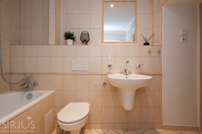 LAURINSKÁ, 2i byt, 68m² – REPREZENTATÍVNE bývanie v historickom CENTRE - Kúpeľňa v 2-izbovom byte s vaňou, umývadlom a toaletou, béžové obklady a dekorácie.