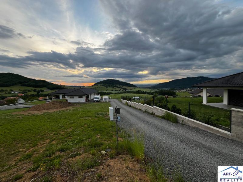 REZERVOVANÉ : Na predaj pozemok v obci Stožok – lokalita Pod Chvojnom - Panoráma obce Stožok so západom slnka a pozemkami na bývanie v kopcovitej krajine.