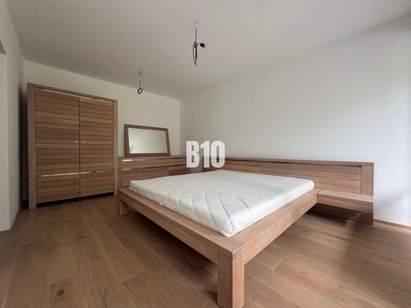 Relax Residence - Apartmán so zariadením - Spálňa v 2-izbovom byte s dreveným nábytkom a podlahou s dreveným dekorom.