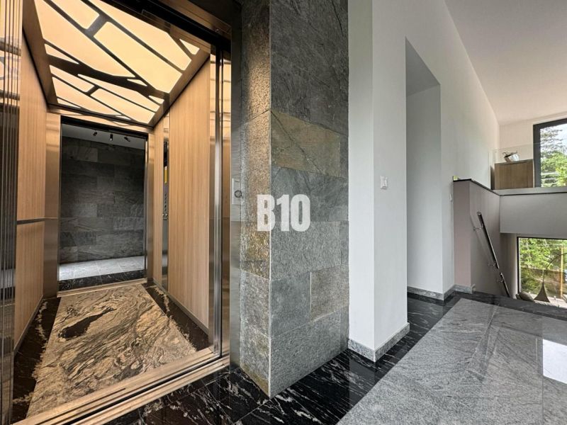 Relax Residence - Apartmán so zariadením - Chodba so štýlovým výťahom v 2-izbovom byte, kamennými stenami a podlahou.
