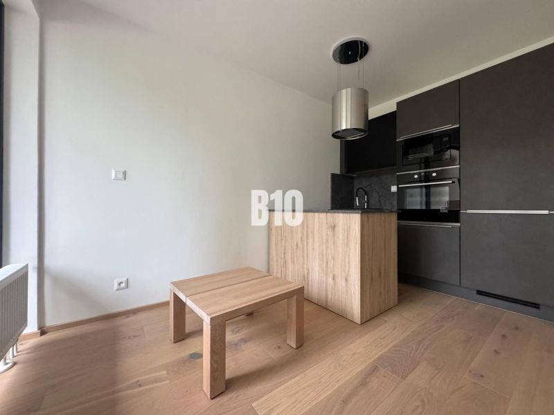 Relax Residence - Apartmán so zariadením - Kuchynský kút s tmavými skrinkami a podlahou s dreveným dekorom v 2-izbovom byte.