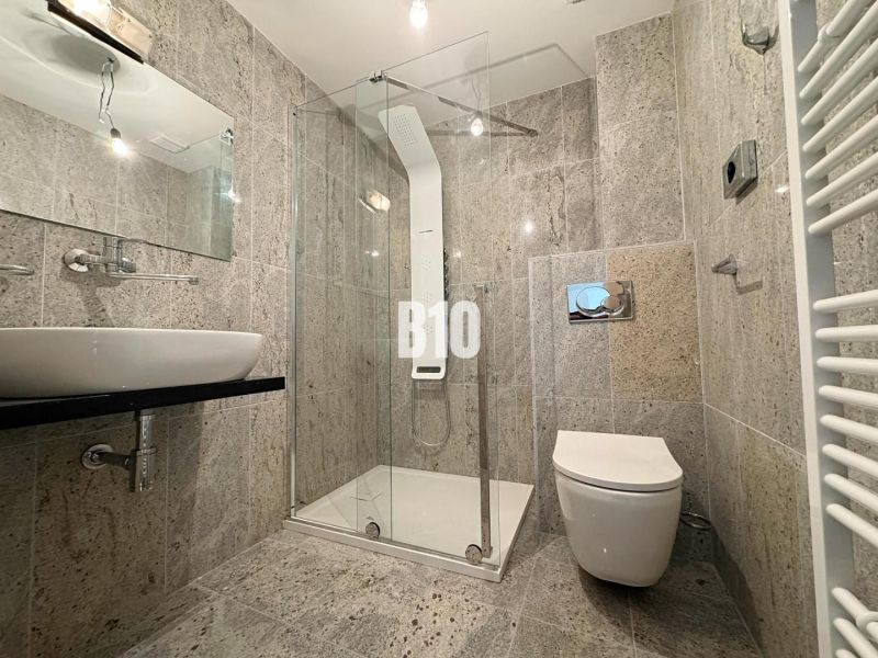 Relax Residence - Apartmán so zariadením - Kúpeľňa v 2-izbovom byte s kamenným obkladom, sprchovacím kútom a zrkadlom.