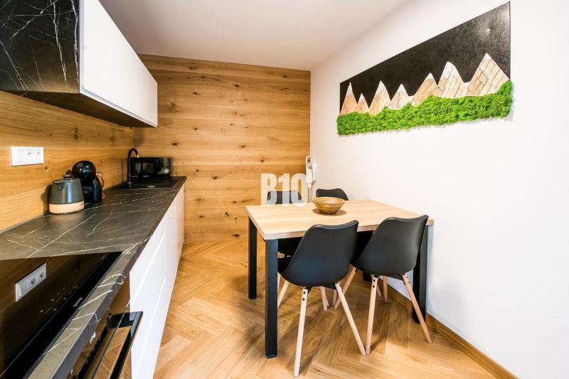 Investičný APARTMÁN v centre Terchovej - Interiér Rekreačného apartmánu s kuchyňou, jedálenským stolom a podlahou s dreveným dekorom.