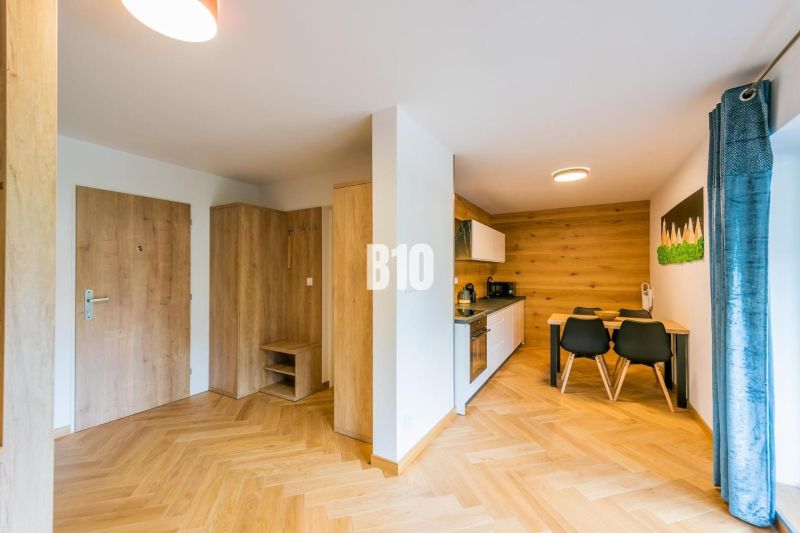 Investičný APARTMÁN v centre Terchovej - Kuchyňa a jedálenský priestor v rekreačnom apartmáne s podlahou s dreveným dekorom.