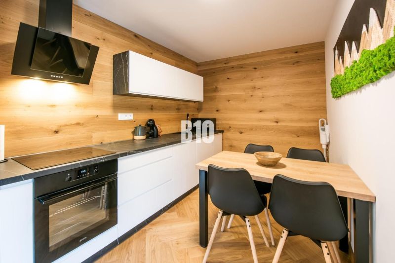 Investičný APARTMÁN v centre Terchovej - Kuchyňa v Rekreačnom apartmáne s podlahou s dreveným dekorom a štýlovým nábytkom.