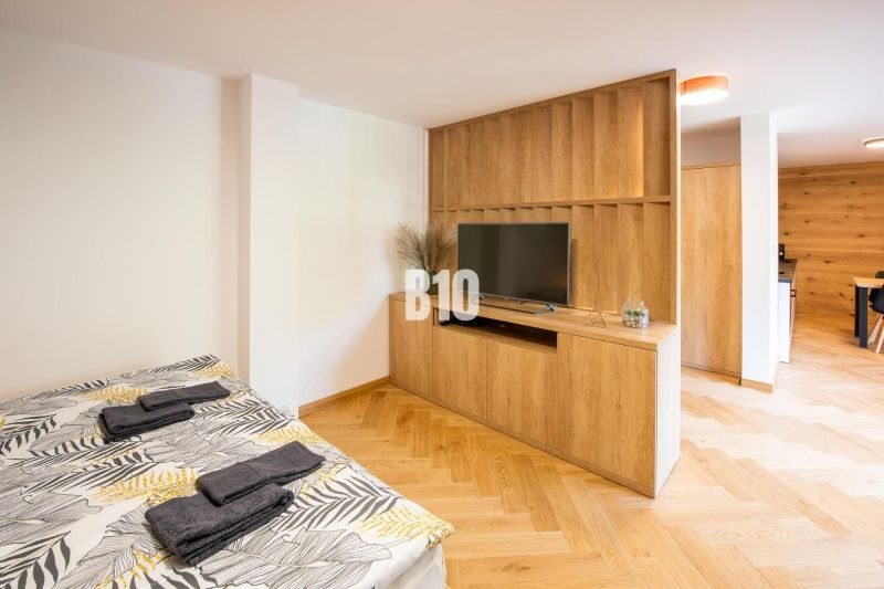 Investičný APARTMÁN v centre Terchovej - Rekreačný apartmán s posteľou, TV, podlahou s dreveným dekorom a dreveným nábytkom.