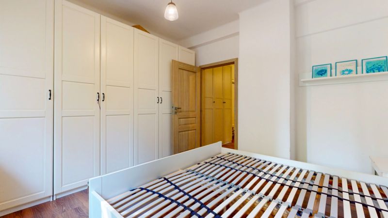 Priestranný 2i byt v obklopení zelene len pár krokov od OC Nivy | 53m² - Spálňa v 2-izbovom byte s bielymi skriňami a podlahou s dreveným dekorom.