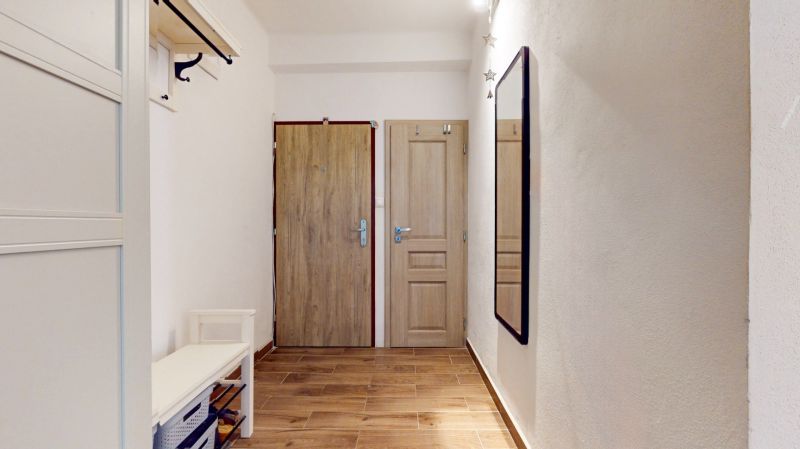 Priestranný 2i byt v obklopení zelene len pár krokov od OC Nivy | 53m² - Chodba s podlahou s dreveným dekorom, zrkadlom a vešiakovou stenou v 2-izbovom byte.