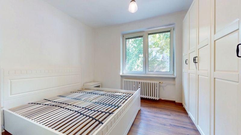 Priestranný 2i byt v obklopení zelene len pár krokov od OC Nivy | 53m² - Svetlá spálňa s bielym posteľným rámom, skriňou a podlahou s dreveným dekorom.
