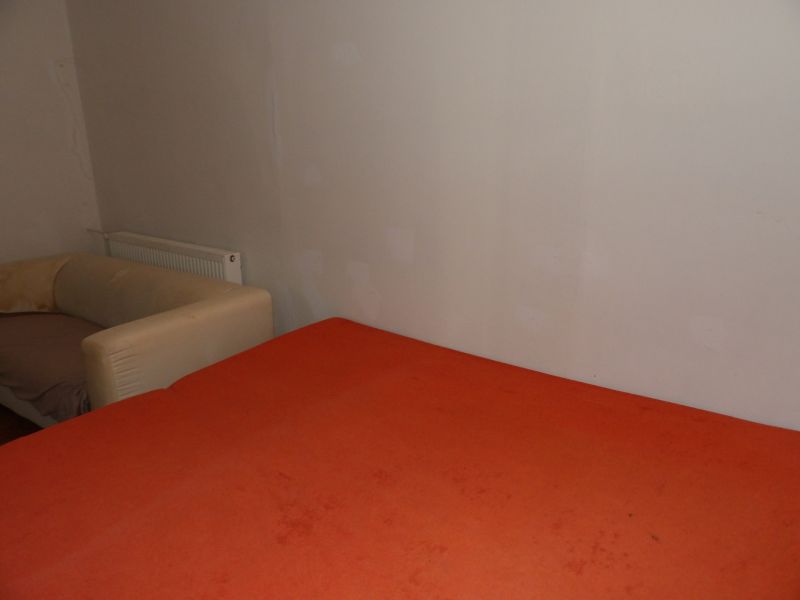 Dvojizbový byt v rodinnom dome v Seredi na prenájom  - Izba s oranžovou posteľou a beige kreslom v 2-izbovom byte.
