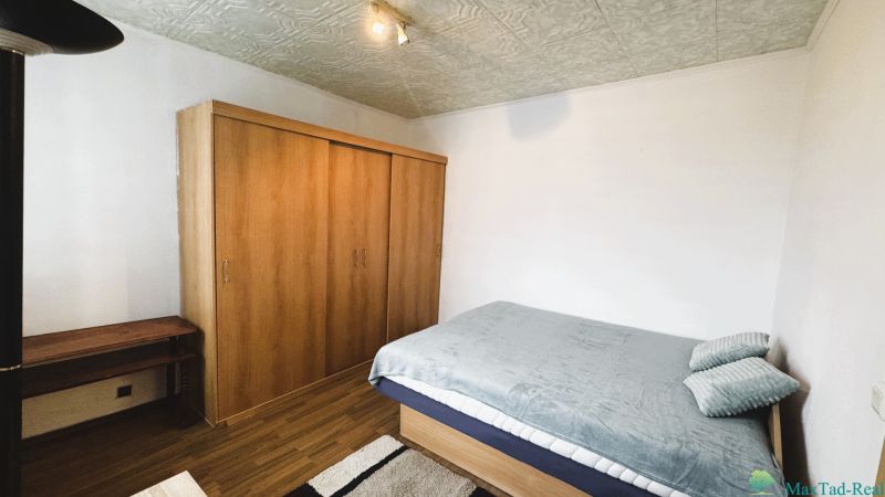 94,66 m², štyri izby a nikto nad hlavou. A Komenského má svoje výhody! - Spálňa v 4-izbovom byte s posteľou, skriňou a podlahou s dreveným dekorom.