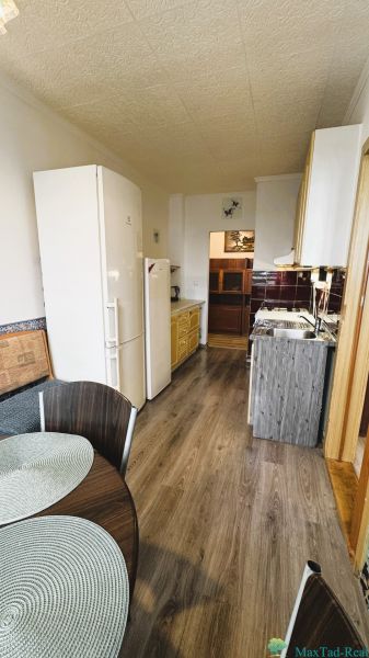 94,66 m², štyri izby a nikto nad hlavou. A Komenského má svoje výhody! - Kuchyňa v 4-izbovom byte s podlahou s dreveným dekorom, jedálenským stolom a spotrebičmi.
