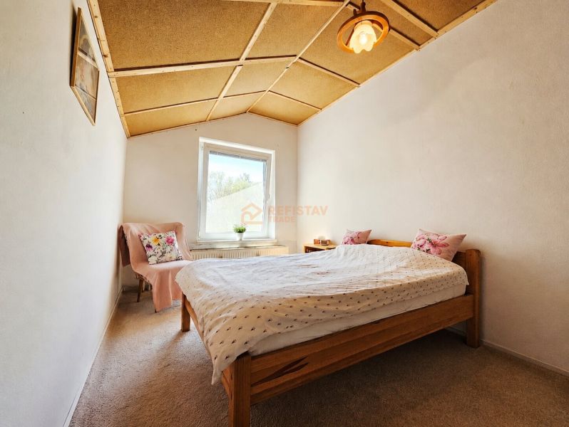 Rodinný dom v okrese Košice - okolie, Nižná Hutka - Spálňa v rodinnom dome s dreveným stropom, kobercom a posteľou s vankúšmi.
