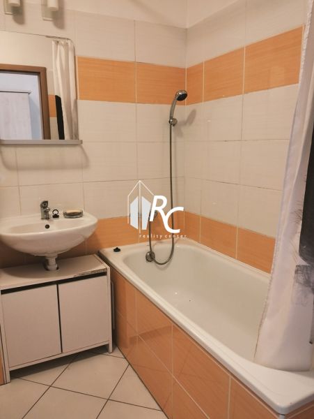 Prenájom dvoch 2-izbových bytov vedľa seba, Martin - centrum - Kúpeľňa v 2-izbovom byte s vaňou a oranžovo-bielymi obkladmi.