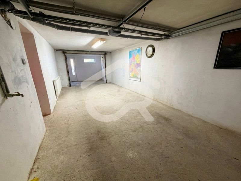 Ponúkam na predaj veľký 4i rodinný dom v tichej slepej ulici - Garáž v rodinnom dome s mapou a hodinami na stene.