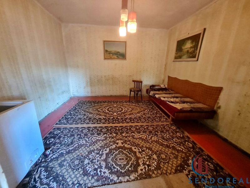 RD Otrokovce 1071m pozemok - Izba v rodinnom dome s kobercom, stoličkou a gaučom.