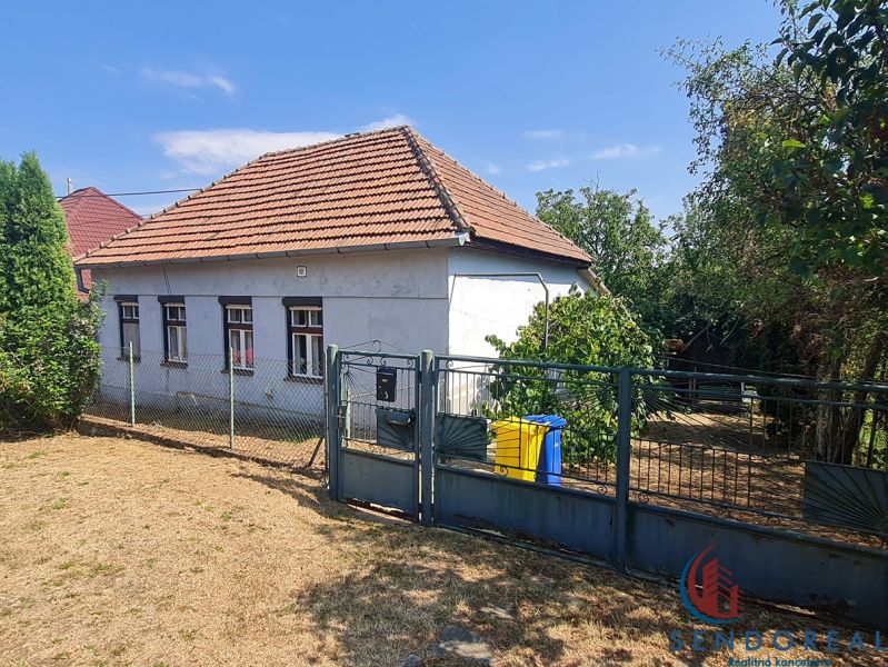 RD Otrokovce 1071m pozemok - Rodinný dom v Dolných Otrokovciach s plotom a záhradou na slnečnom pozemku.