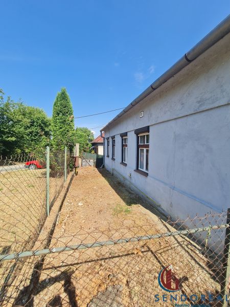 RD Otrokovce 1071m pozemok - Rodinný dom v Dolných Otrokovciach s oplotením a príjazdovou cestou na dvore.