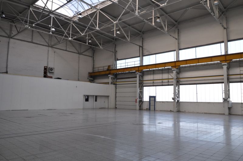 Priemyselná hala 2 500 m²  SKLADOVANIE, VÝROBA, LOGISTIKA - Výrobné priestory s vysokým stropom, oknami a betónovou podlahou.