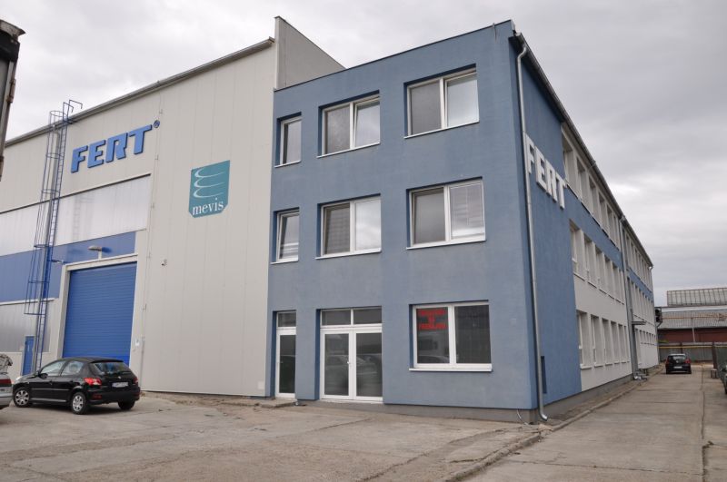 Priemyselná hala 2 500 m²  SKLADOVANIE, VÝROBA, LOGISTIKA - Výrobné priestory na Priemyselnej ulici v Galante so sivou budovou a parkoviskom.