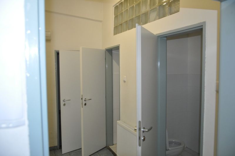 Priemyselná hala 2 500 m²  SKLADOVANIE, VÝROBA, LOGISTIKA - Otvorené dvere na toalete vo výrobných priestoroch s dlažbou a umývadlom.