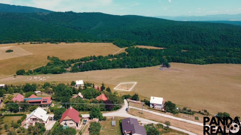 POZEMOK NA VÝSTAVBU PODHRADIE - Vidiecky pohľad na pozemky na bývanie v Podhradí obklopené lesmi a lúkami.