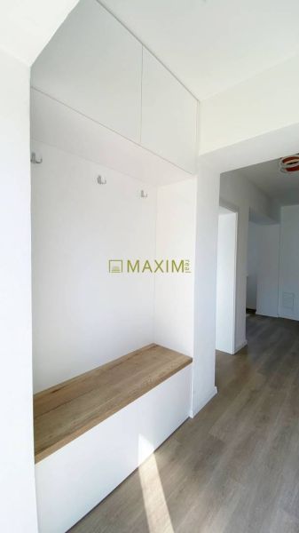 Bývajte v prírode, ostaňte v Bratislave! - Interiér rodinného domu s bielou skriňou, lavičkou a podlahou s dreveným dekorom.