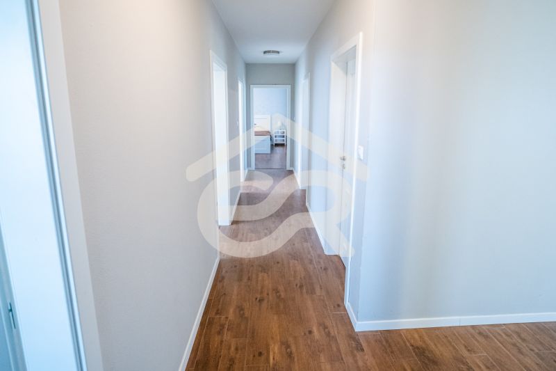 Na predaj 5i rodinný dom, novostavba, Vráble, pozemok 1200m2 - Chodba v rodinnom dome s podlahou s dreveným dekorom a bielymi stenami.