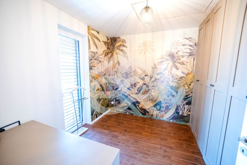 Na predaj 5i rodinný dom, novostavba, Vráble, pozemok 1200m2 - Izba v Rodinnom dome s exotickou tapetou a podlahou s dreveným dekorom.