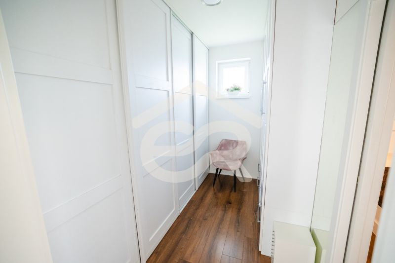 Na predaj 5i rodinný dom, novostavba, Vráble, pozemok 1200m2 - Úzka chodba v rodinnom dome s podlahou s dreveným dekorom a oknom.