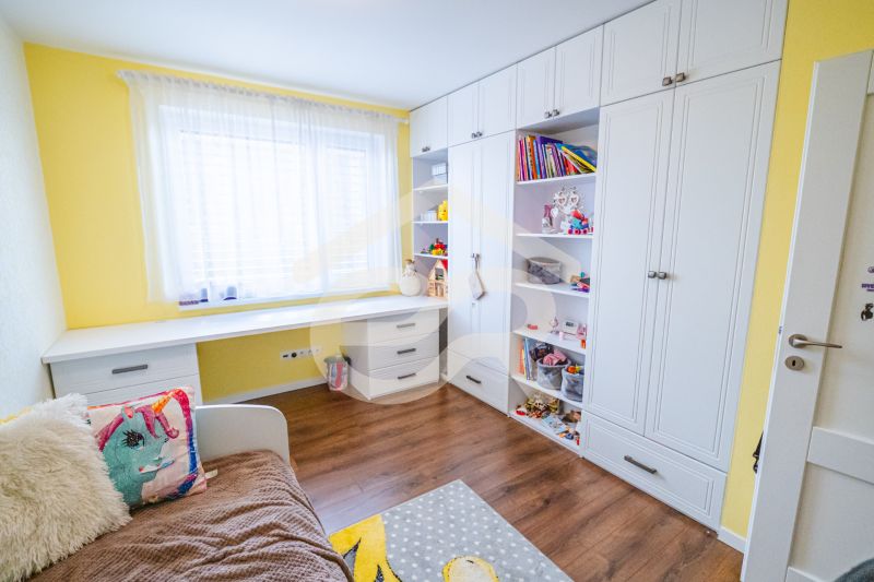 Na predaj 5i rodinný dom, novostavba, Vráble, pozemok 1200m2 - Detská izba s posteľou, policovou skriňou a podlahou s dreveným dekorom v rodinnom dome.