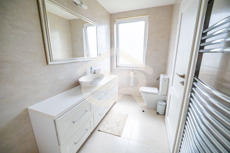 Na predaj 5i rodinný dom, novostavba, Vráble, pozemok 1200m2 - Kúpeľňa v rodinnom dome s bielym umývadlom a veľkým zrkadlom.