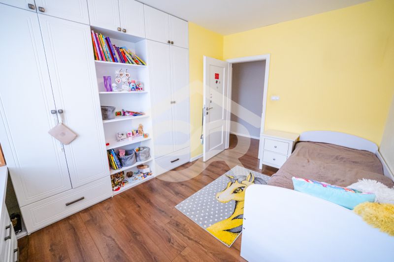 Na predaj 5i rodinný dom, novostavba, Vráble, pozemok 1200m2 - Detská izba v rodinnom dome s bielou skriňou, hnedou posteľou a podlahou s dreveným dekorom.