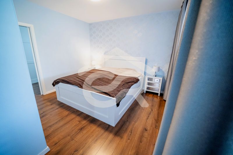 Na predaj 5i rodinný dom, novostavba, Vráble, pozemok 1200m2 - Spálňa v rodinnom dome s posteľou, nočnými stolíkmi a podlahou s dreveným dekorom.