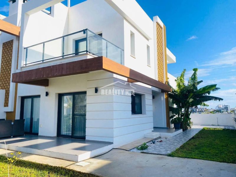 MODERNÁ VILA 3+1 S VÝHĽADOM NA MORE A HORY | YENİ BOĞAZİÇİ, - Rodinný dom v Yeni Boğaziçi s terasou, trávnikom a palmami v záhrade.