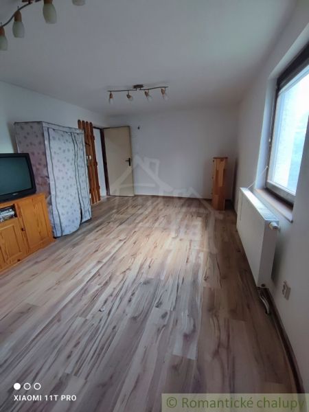 INVESTIČNÁ PRÍLEŽITOSŤ: Flexibilný objekt na bývanie aj podnikanie15 m - Izba v rodinnom dome s televíziou a podlahou s dreveným dekorom.
