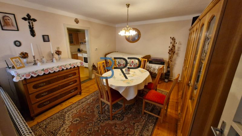 Mokrý Háj - predaj dom - Jedáleň v rodinnom dome s dreveným dekorom, stolom a komodou.