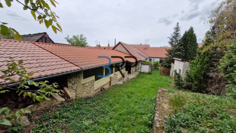 Mokrý Háj - predaj dom - Záhrada pri rodinnom dome v Mokrém Háji s kamenným múrom a červenou strešnou krytinou.