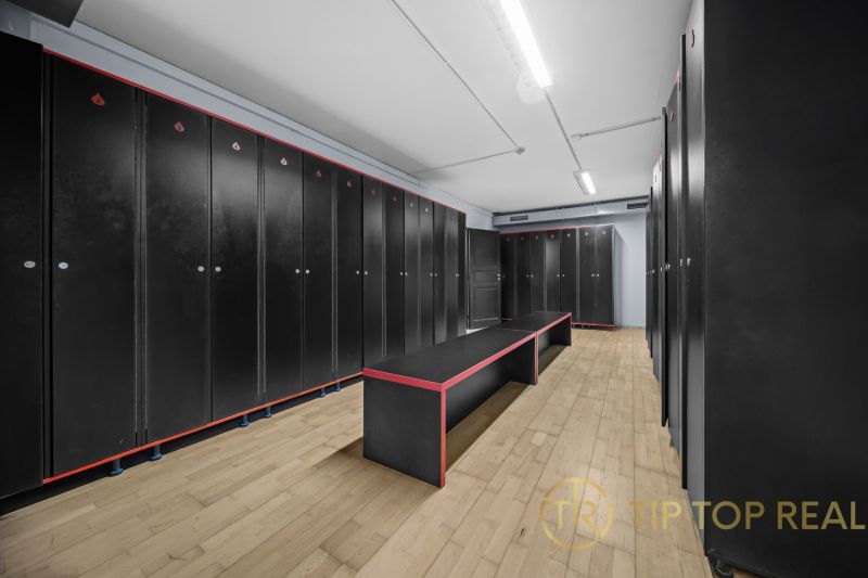 Na predaj PRIESTRANNÉ FITNESS CENTRUM na LUKRATÍVNEJ ADRESE RUŽINOVA - Čierne skrinky, lavice s kontrastným dizajnom, podlaha s dreveným dekorom v obchodných priestoroch.