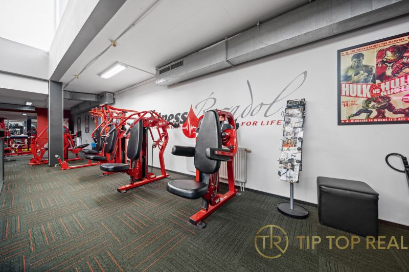 Na predaj PRIESTRANNÉ FITNESS CENTRUM na LUKRATÍVNEJ ADRESE RUŽINOVA - Posilňovacie stroje v obchodných priestoroch so zrkadlami a kobercovou podlahou.
