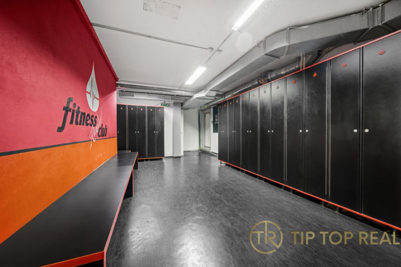 Na predaj PRIESTRANNÉ FITNESS CENTRUM na LUKRATÍVNEJ ADRESE RUŽINOVA - Fitness šatňa s čiernymi skrinkami a červenou stenou v obchodných priestoroch.