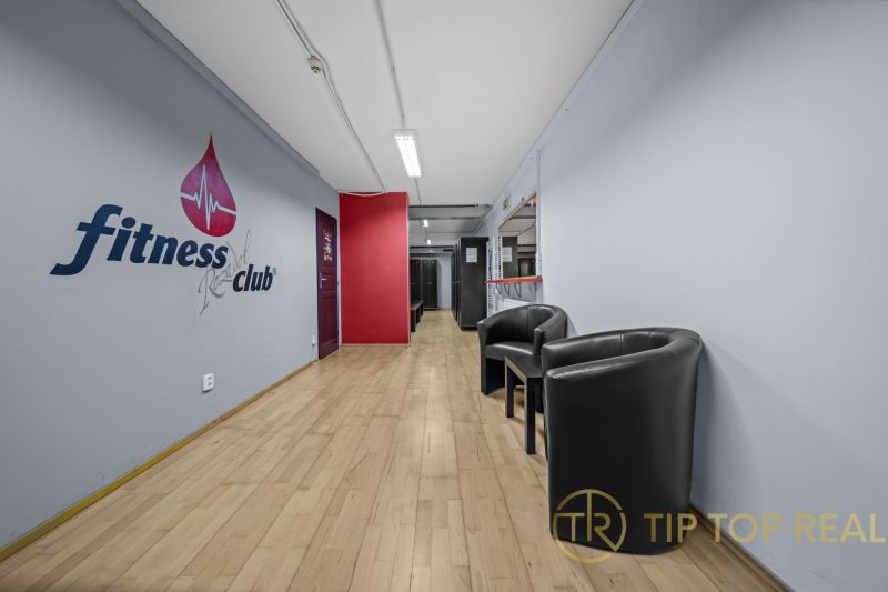 Na predaj PRIESTRANNÉ FITNESS CENTRUM na LUKRATÍVNEJ ADRESE RUŽINOVA - Interiér obchodných priestorov s podlahou s dreveným dekorom a pohodlnými kreslami.