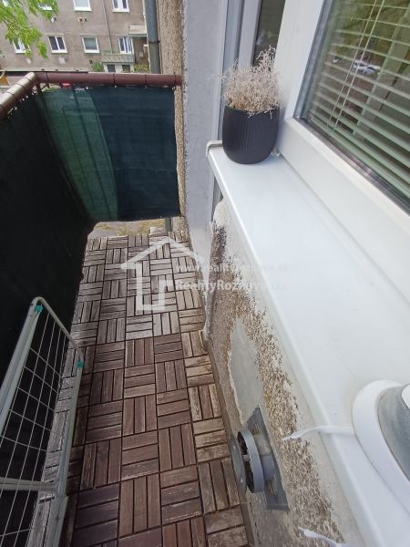 Krásny 2 izbový byt s balkónom- Vargové pole. - Balkón v 2-izbovom byte s podlahou s dreveným dekorom a kvetináčom.