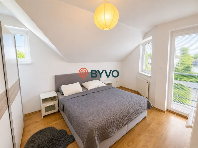 6-izbový rodinný dom v Šamoríne | 201 m² | pozemok 451 m² | - Spálňa so strešnými oknami, sivou posteľou a podlahou s dreveným dekorom v rodinnom dome.