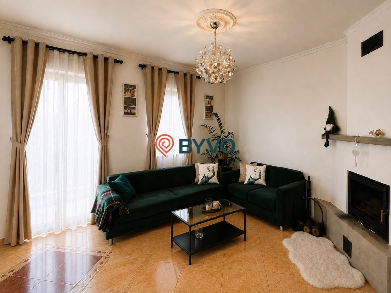 6-izbový rodinný dom v Šamoríne | 201 m² | pozemok 451 m² | - Obývačka v rodinnom dome s tmavozelenou sedačkou, kozubom a veľkými oknami.