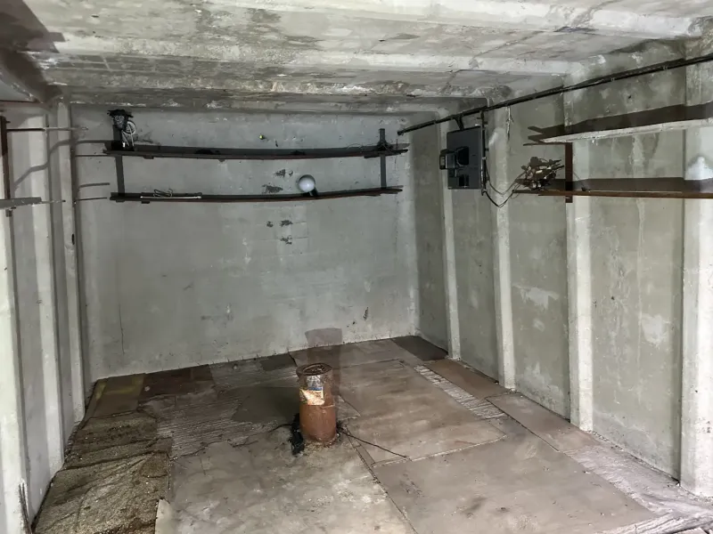18 m2 Garáž na Sliačskej ulici v Bratislave - Betónová miestnosť s držiakmi na stene a podlahou s dreveným dekorom v garážach.
